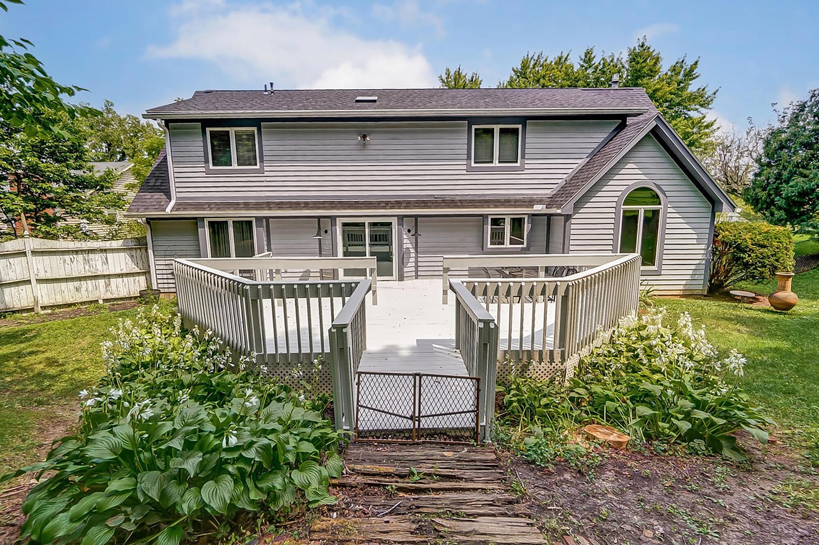 The rear of the home has a two level wood deck with railings and a partial privacy fence.