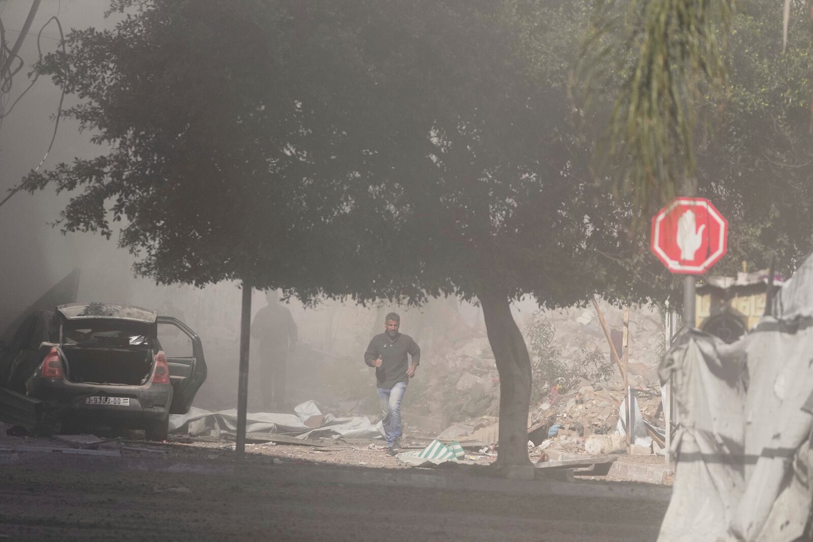 Palestinians run away from a blast following an Israeli army strike, in central Gaza on Sunday, March 23, 2025. (AP Photo/Jehad Alshrafi)