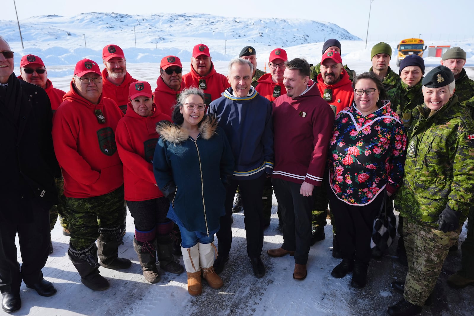 Canada's Defence Minister Bill Blair, front left, Nunavut MLA Janet Brewster, Canada's Prime Minister Mark Carney, Nunavut Premier P.J. Akeeagok, Nunavut Education Minister Pamela Gross, Chief of Defence Staff Gen. Jennie Carignan, along with members of the Canadian Rangers, back left, and members of the Canadian Armed Forces, back right, pose for a photo after an announcement at a Canadian Armed Forces forward-operating location in Iqaluit, Nunavut, Tuesday, March 18, 2025. (Sean Kilpatrick/The Canadian Press via AP)