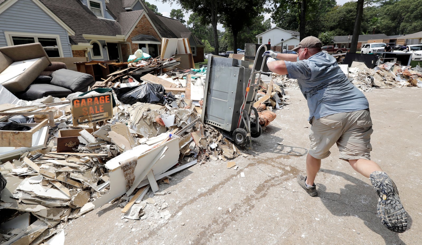 FILE - Volunteer Paul Hancock pushes an oven damaged by floodwaters onto a pile of debris in the aftermath of Hurricane Harvey in Spring, Texas, on Sept. 3, 2017. (AP Photo/David J. Phillip, File)