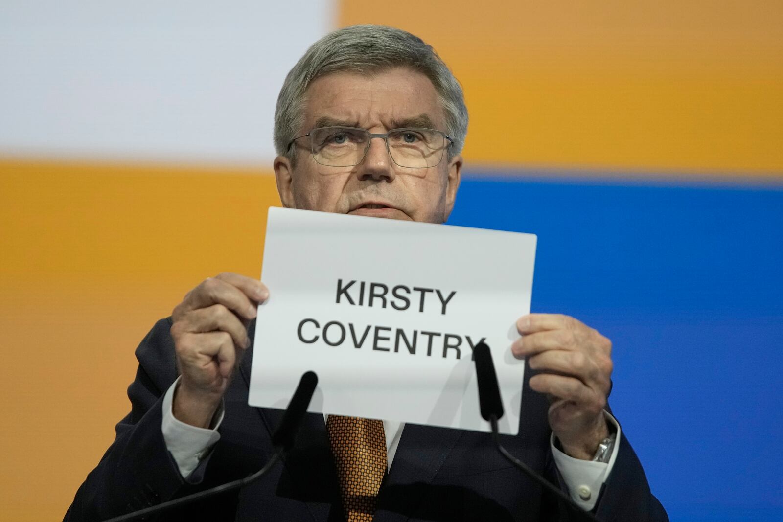 IOC President Thomas Bach holds up the name of Kirsty Coventry as she is announced as the new IOC President at the International Olympic Committee 144th session in Costa Navarino, western Greece, Thursday, March 20, 2025. (AP Photo/Thanassis Stavrakis)