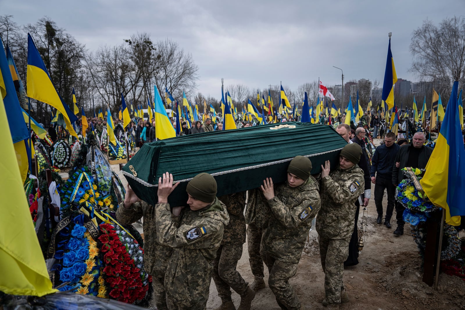 FILE - Ukrainian servicemen carry the coffin of their comrade Andrii Neshodovskiy during the funeral ceremony at the cemetery in Kyiv, Ukraine, Saturday, March 25, 2023. (AP Photo/Evgeniy Maloletka, File)