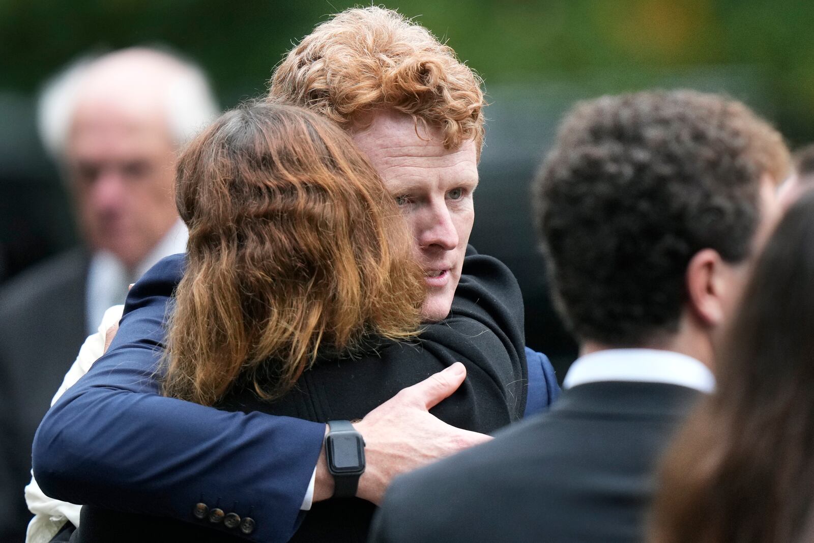 Joseph Kennedy III, center right, grandson of Ethel Kennedy, hugs fellow mourners following funeral services at Our Lady of Victory church for Ethel Kennedy, Monday, Oct. 14, 2024, in Centerville, Mass. (AP Photo/Steven Senne)