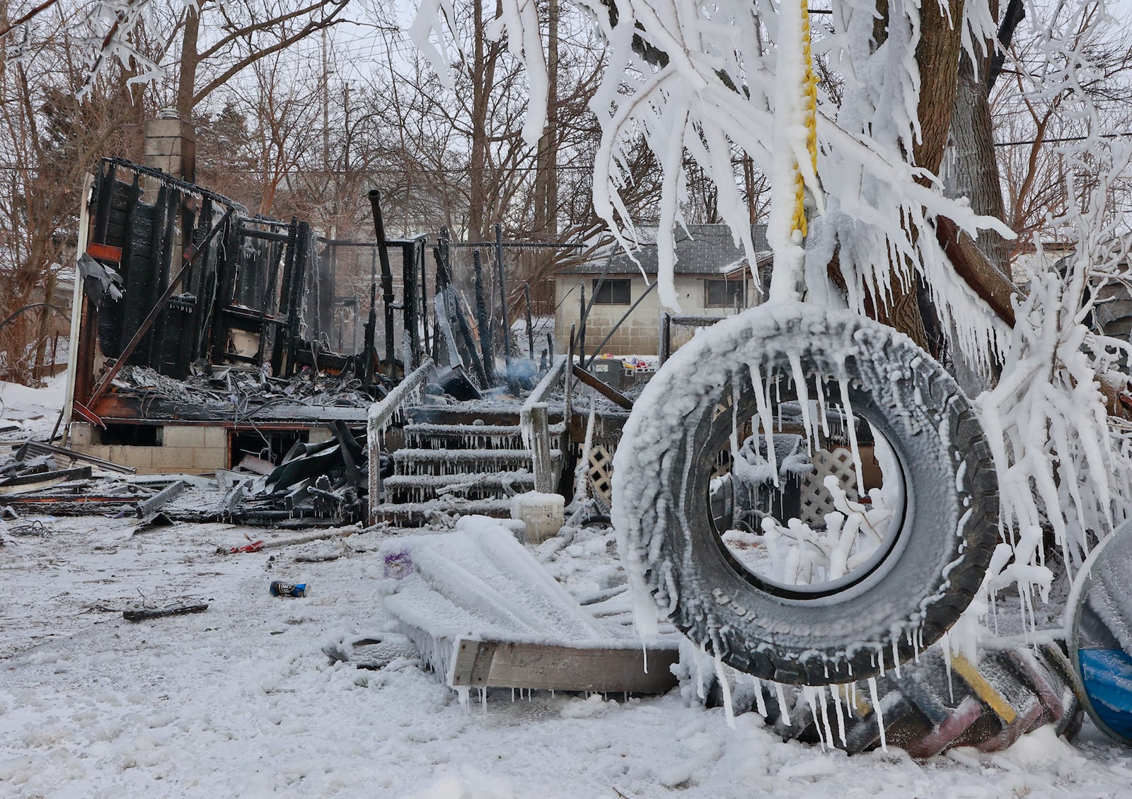 A tire swing is coated in ice in front of a smoldering remains of a house in the 300 block of Lyle Avenue in Springfield Township Friday morning. The Springfield Township fire department responded to the fully involved fire early Friday morning, Dec. 23, 2022. Brutal cold weather and strong winds hampered firefighting efforts. BILL LACKEY/STAFF