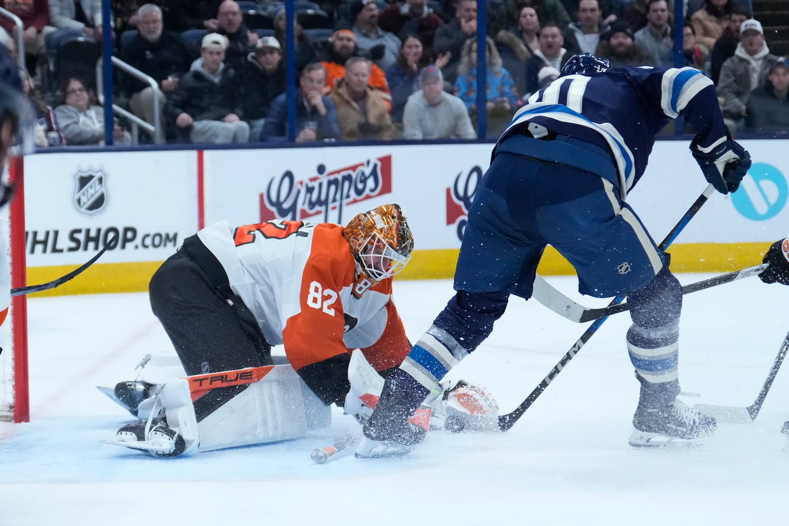 Philadelphia Flyers goaltender Ivan Fedotov (82) reaches to cover the puck next to Columbus Blue Jackets left wing Dmitri Voronkov (10) in the second period of an NHL hockey game Tuesday, Jan. 14, 2025, in Columbus, Ohio. (AP Photo/Sue Ogrocki)