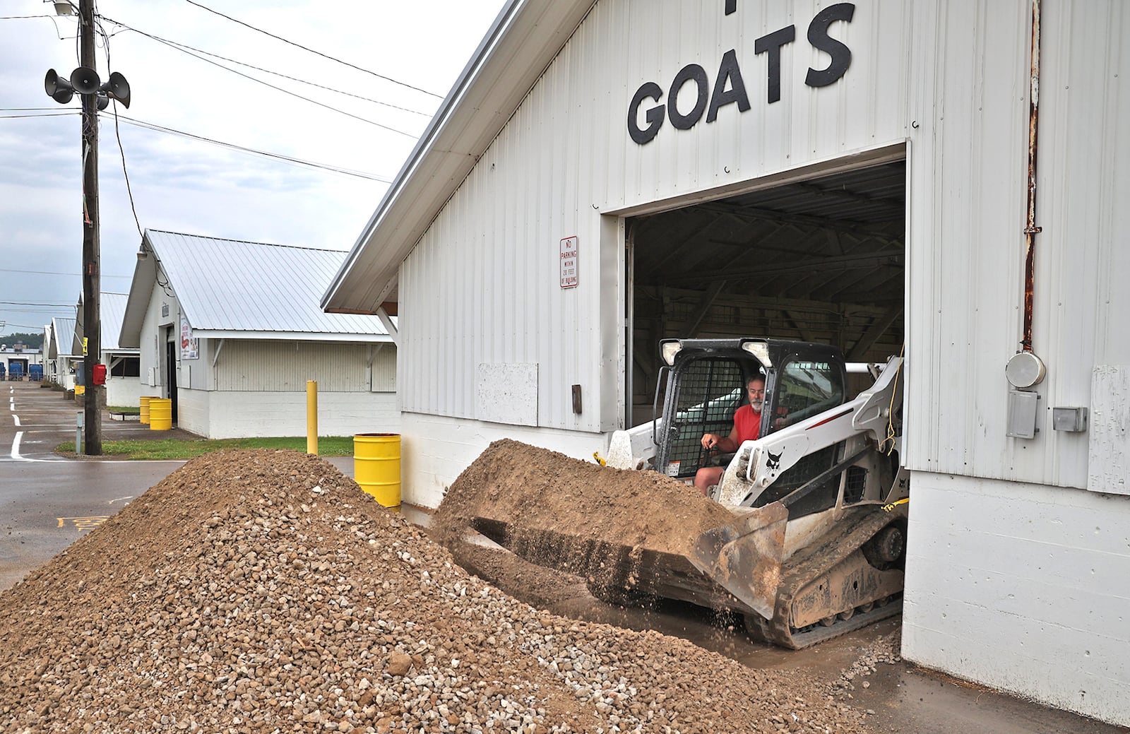 A work crew at the Clark County Fairgrounds puts down new gravel for the floor of the Goat Barn Friday as they get ready for the upcoming fair. BILL LACKEY/STAFF