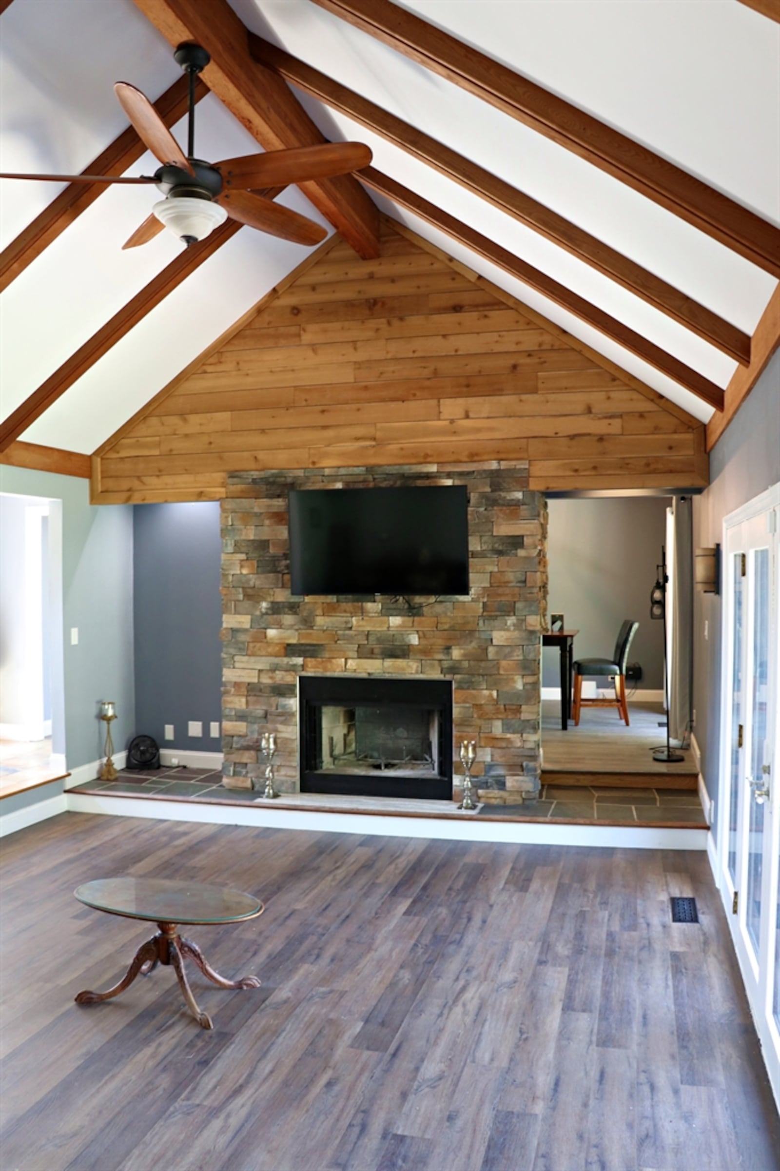 The sunken great room features a cathedral ceiling with wood beams that gather at the center beam at the peak. 