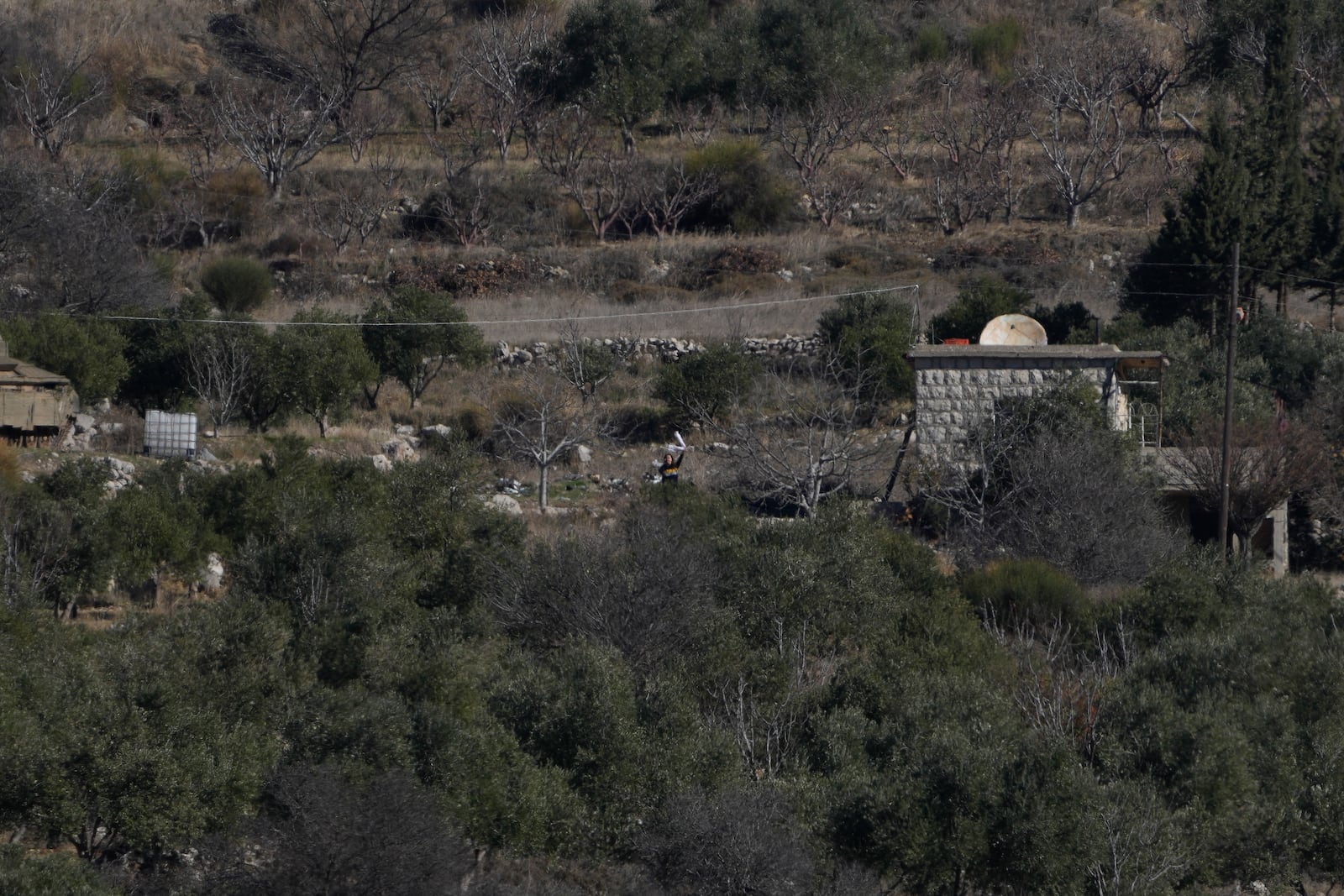 Sawsan, one of six Safadi sisters, standing inside the buffer zone, waves to her sisters near the "Alpha Line" that separates the Israeli-controlled Golan Heights from Syria, seen from the town of Majdal Shams, Wednesday, Dec. 18, 2024. (AP Photo/Matias Delacroix)