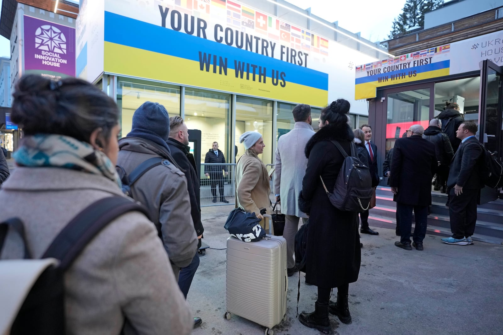 People line up in front of the Ukraine house to watch the inauguration of Donald Trump on screens alongside the World Economic Forum in Davos,Switzerland, Monday, Jan. 20, 2025. (AP Photo/Markus Schreiber)