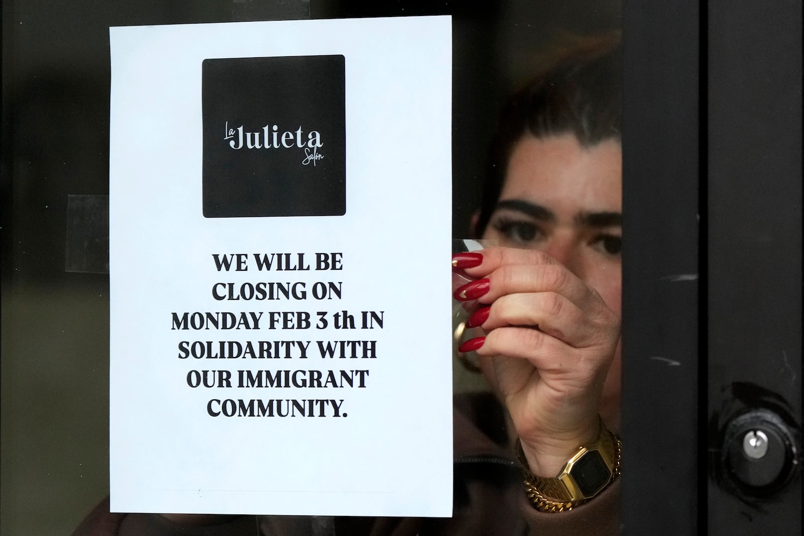 Andrea Toro, owner of La Julieta Salon, tapes a closure sign on her store in the Pilsen neighborhood of Chicago, to stand with immigrants, Monday, Feb. 3, 2025. (AP Photo/Nam Y. Huh)