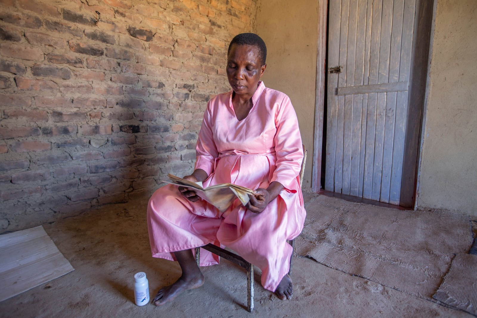 Florence Makumene, 53, poses with her HIV medication and a hospital records book at her home in Harare, Zimbabwe, Friday, Feb. 7, 2025. (AP Photo/Aaron Ufumeli)