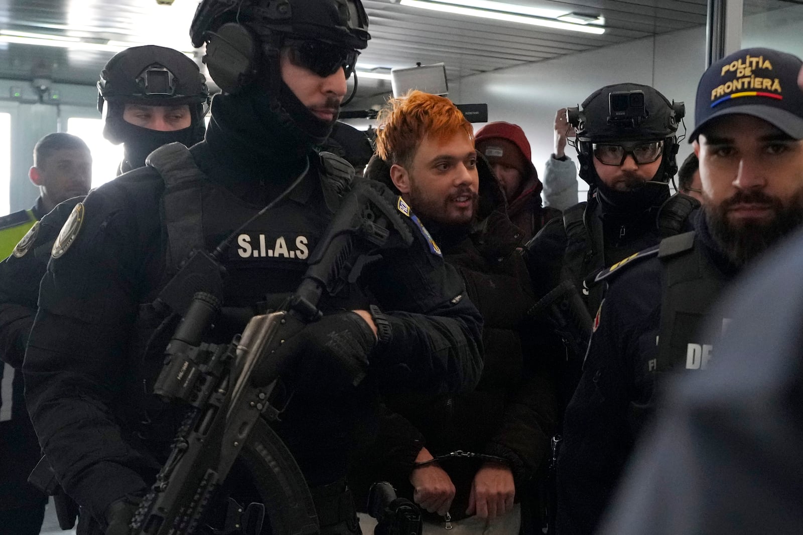 Mohamed Amra, nicknamed ''The Fly", is escorted by armed police officers at the Henri Coanda international airport in Otopeni, Romania, Tuesday, Feb. 25, 2025, before being extradited to France. (AP Photo/Vadim Ghirda)