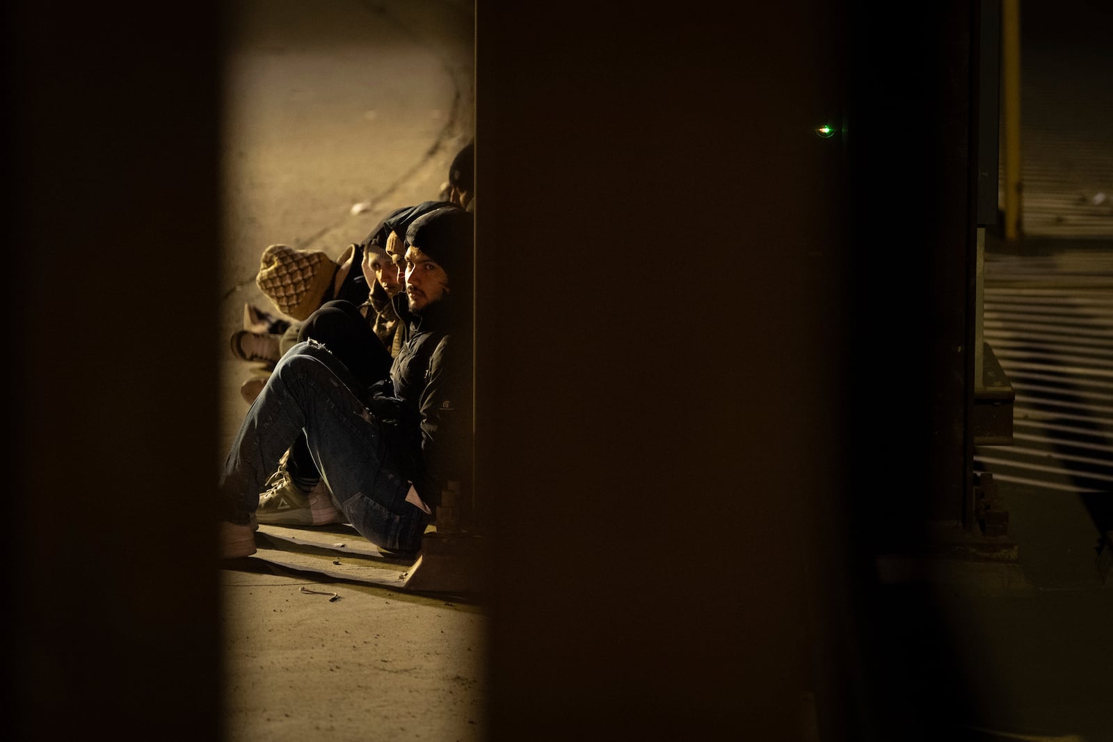 A group of migrants wait to be processed between to border walls separating Mexico and the United States after crossing illegally before dawn Tuesday, Jan. 21, 2025, in San Diego. (AP Photo/Gregory Bull)