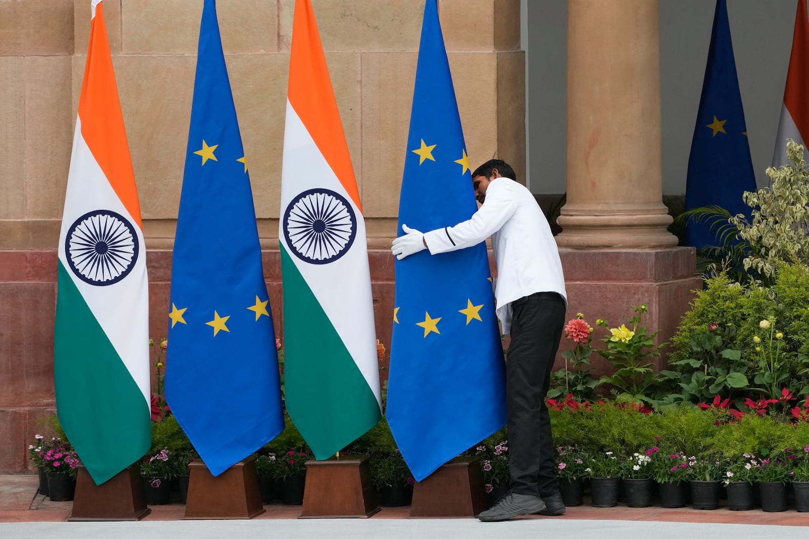 A worker adjusts a European Commission flag placed at the venue for the meeting between Indian Prime Minister Narendra Modi and European Commission President Ursula von der Leyen in New Delhi, India, Friday, Feb. 28, 2025. (AP Photo/Manish Swarup)