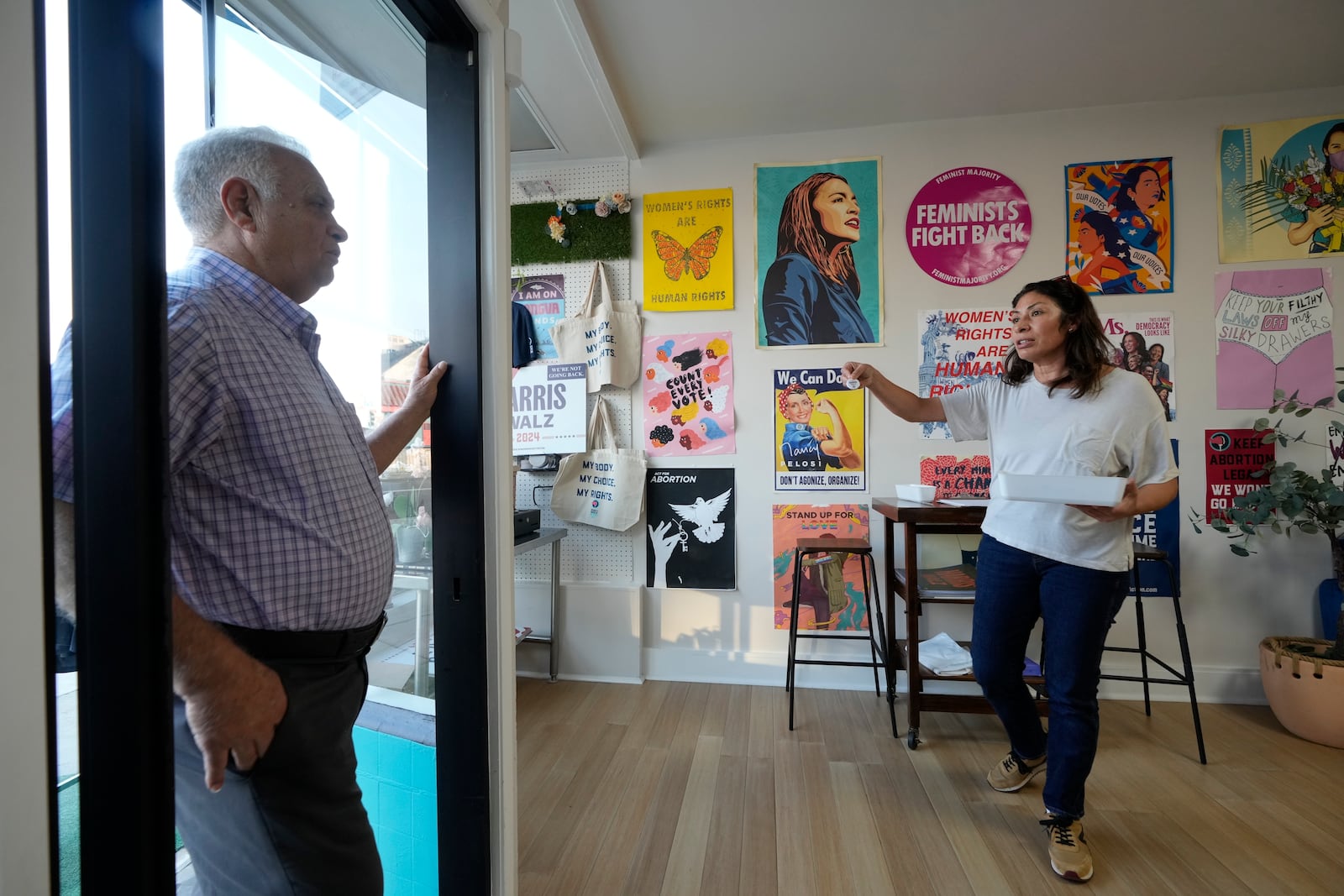 Emiliana Guereca, founder and president of the Women's March Foundation, speaks with neighbor Ignacio Valencia Vergara from a phone bank where volunteers are calling voters to encourage them to vote for Democratic presidential nominee Vice President Kamala Harris on Tuesday, Oct. 15, 2024, in Los Angeles. (AP Photo/Damian Dovarganes)