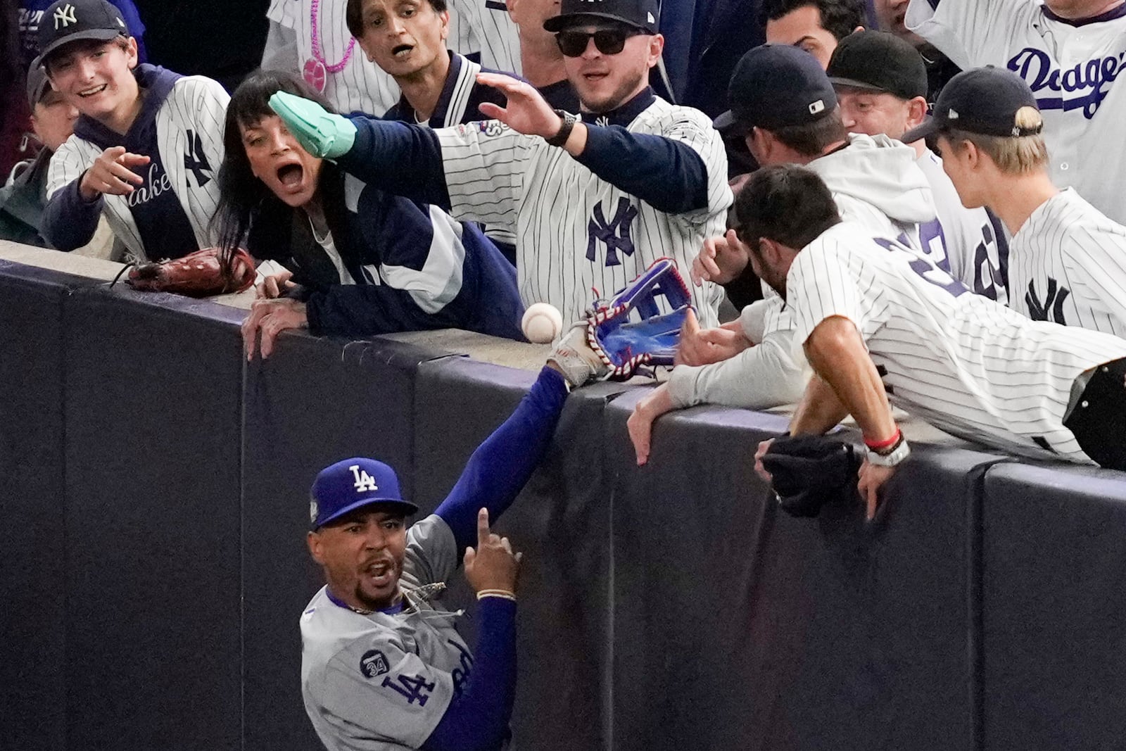 FILE - Fans interfere with a foul ball caught by Los Angeles Dodgers right fielder Mookie Betts during the first inning in Game 4 of the baseball World Series against the New York Yankees, Tuesday, Oct. 29, 2024, in New York. (AP Photo/Ashley Landis, File)