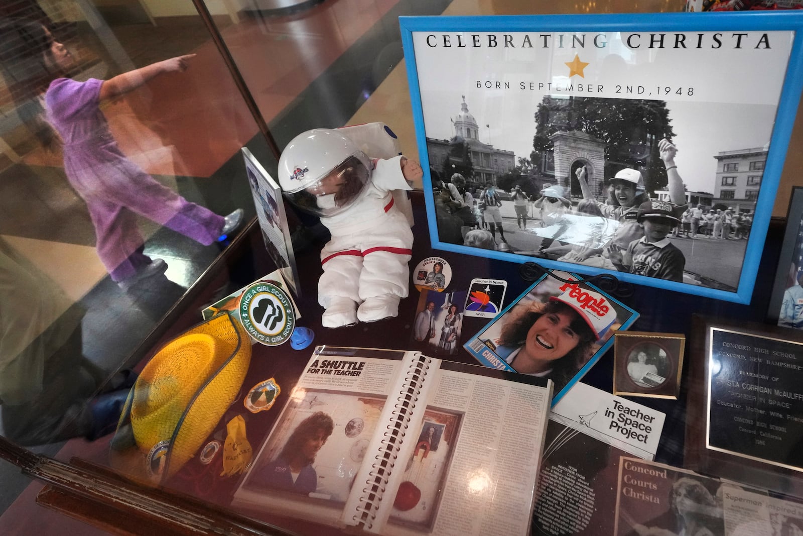 A student passes a selection of memorabilia featuring Christa McAuliffe, NASA's first teacher in space, is displayed at the McAuliffe-Shepard Discovery Center, Monday, Dec. 16, 2024, in Concord, N.H. (AP Photo/Charles Krupa)