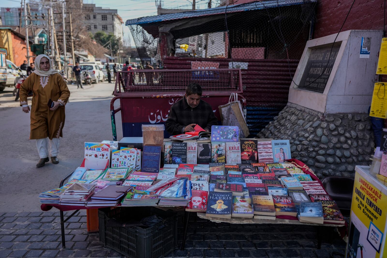 A street vender waits for customers as he sells books in Srinagar, Indian controlled Kashmir, Monday, Feb. 17, 2025. (AP Photo/Mukhtar Khan)