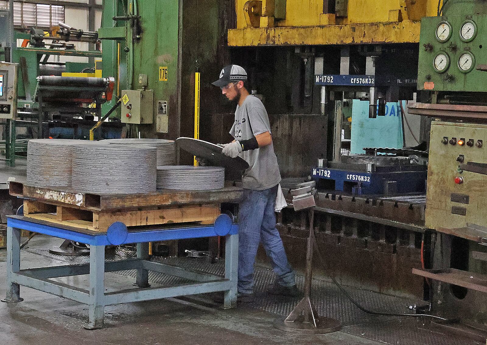 A worker at Pentaflex puts a blank into a stamping press Wednesday. BILL LACKEY/STAFF