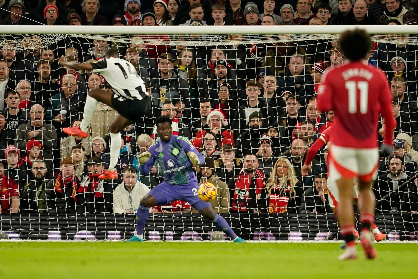 Newcastle's Alexander Isak, left, scores his side's opening goal during the English Premier League soccer match between Manchester United and Newcastle at the Old Trafford stadium in Manchester, England, Monday, Dec. 30, 2024. (AP Photo/Dave Thompson)