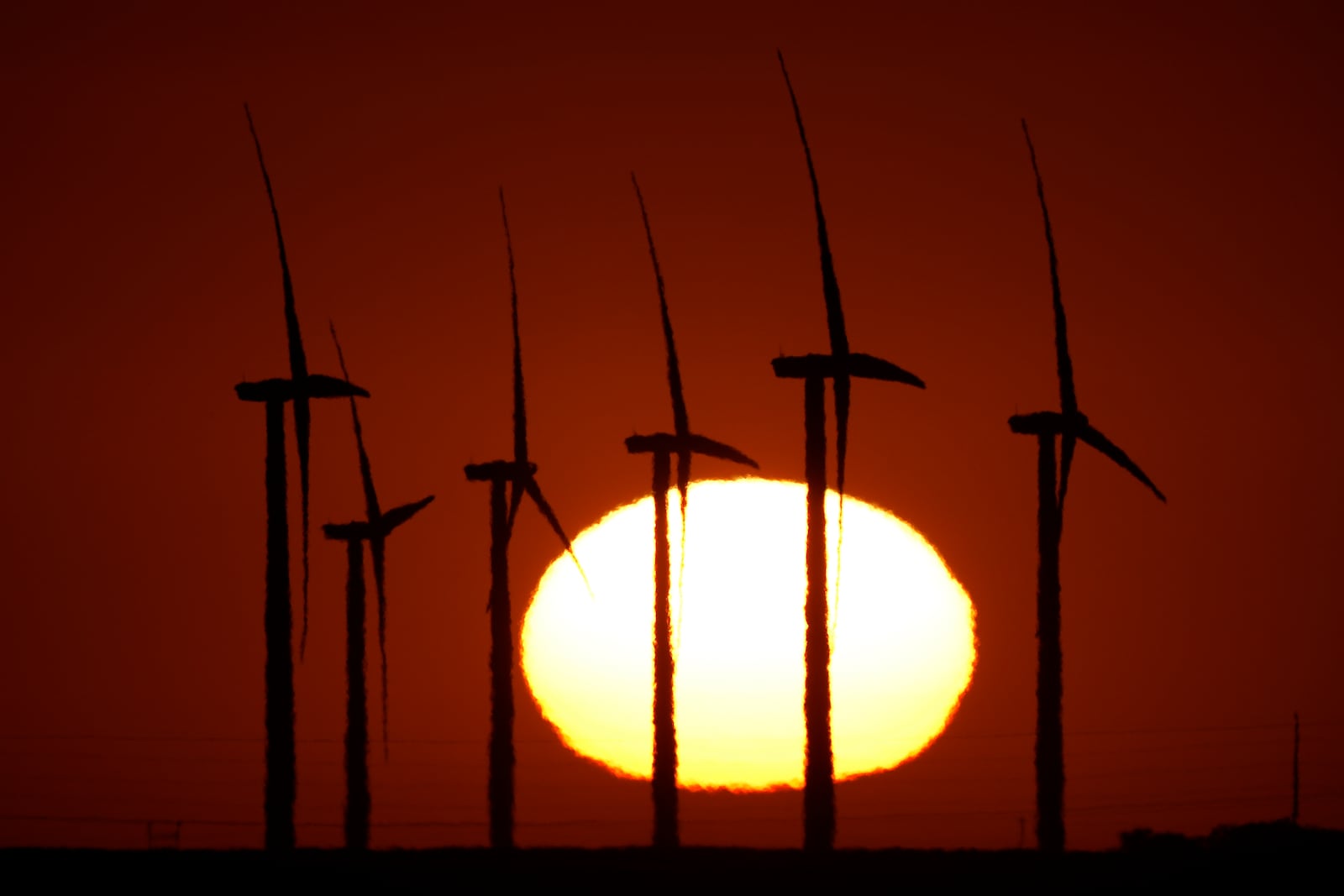 FILE - Wind turbines at the Buckeye Wind Energy are diffused by heat vapors as the are silhouetted against the rising sun, Sept. 30, 2024, near Hays, Kan. (AP Photo/Charlie Riedel, File)