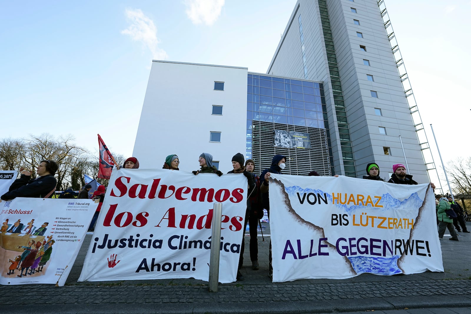 Climate activists protest in front of the Higher Regional Court in Hamm, Germany, for a first hearing of a climate damages case of plaintiff Peruvian farmer Luciano Lliuya against the German energy company RWE for its carbon emissions, which may have been contributing to the melting of a nearby glacier that could flood his home, Monday, March 17, 2025. (AP Photo/Martin Meissner)