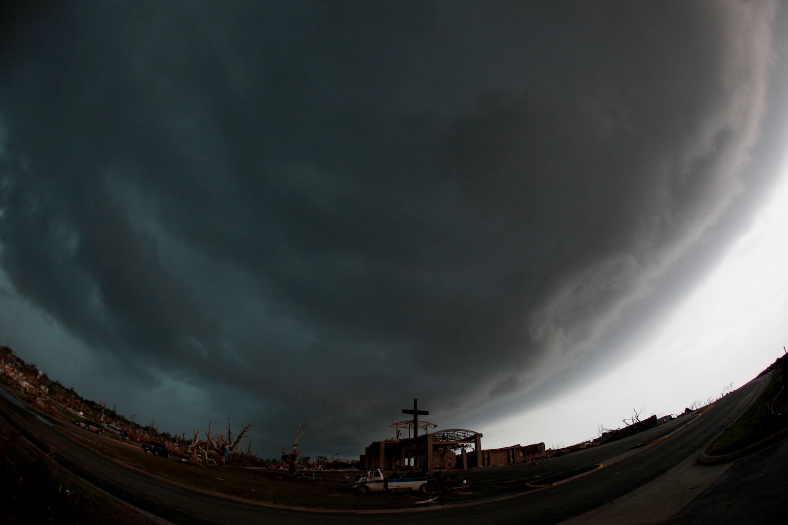 FILE- A cross stands atop a church that was severely damaged by a tornado in Joplin, Mo., as a severe storm passes overhead Monday, May 23, 2011. (AP Photo/Charlie Riedel, File)