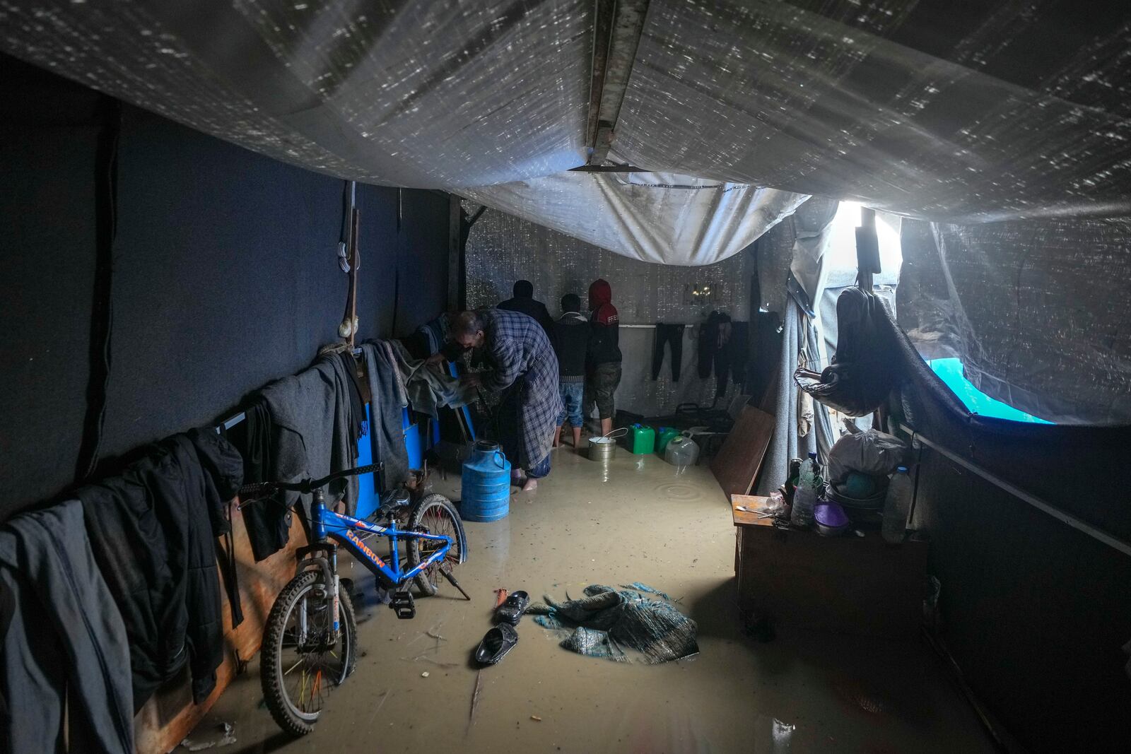 Nabil Lubbad tries to clean his family's flooded tent after heavy overnight rainfall at the refugee tent camp for displaced Palestinians in Deir al-Balah, central Gaza Strip, Tuesday, Dec. 31, 2024. (AP Photo/Abdel Kareem Hana)