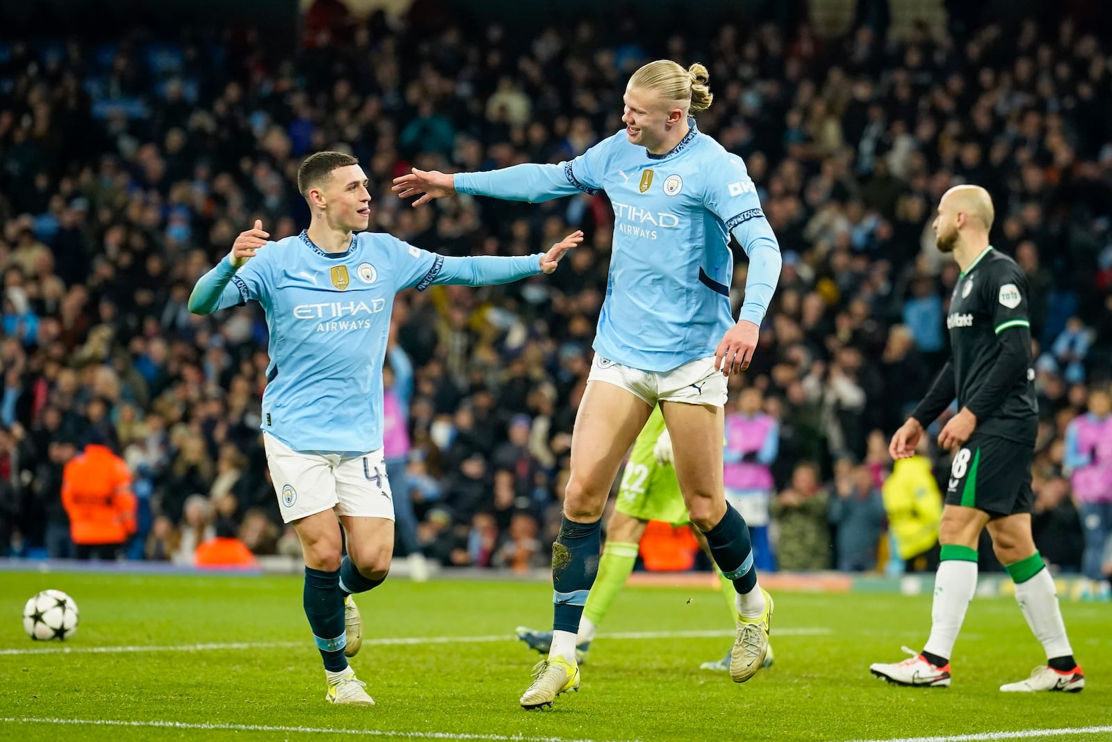 Manchester City's Erling Haaland, center, celebrates with Phil Foden, left, after scoring his side's third goal during the Champions League opening phase soccer match between Manchester City and Feyenoord at the Etihad Stadium in Manchester, England, Tuesday, Nov. 26, 2024. (AP Photo/Dave Thompson)