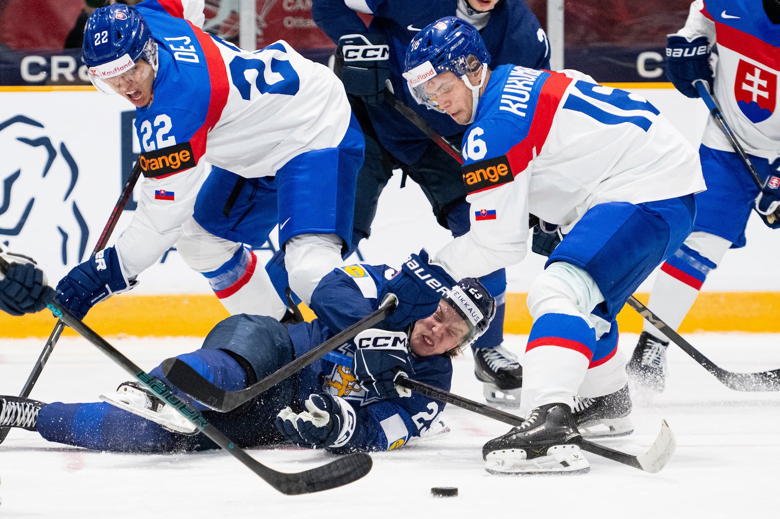 Finland forward Arttu Alasiurua (29) falls to the ice as Slovakia forward Frantisek Dej (22) and teammate Roman Kukumberg (16) battle for the puck during the first period of an IIHF World Junior Hockey Championship quarterfinal match in Ottawa, Ontario Thursday, Jan. 2, 2025. (Spencer Colby/The Canadian Press via AP)