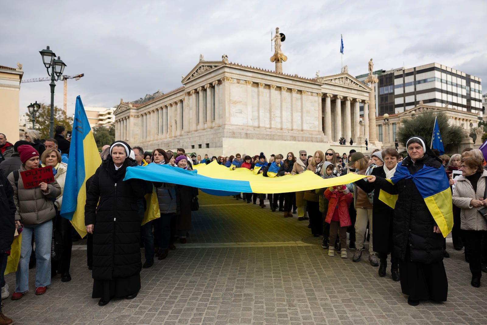 Protesters carry a Ukrainian flag during a rally ahead of the three year anniversary of the Russian invasion of Ukraine, in front of the Athens Academy, Greece, on Sunday, Feb. 23, 2025. (AP Photo/Yorgos Karahalis)