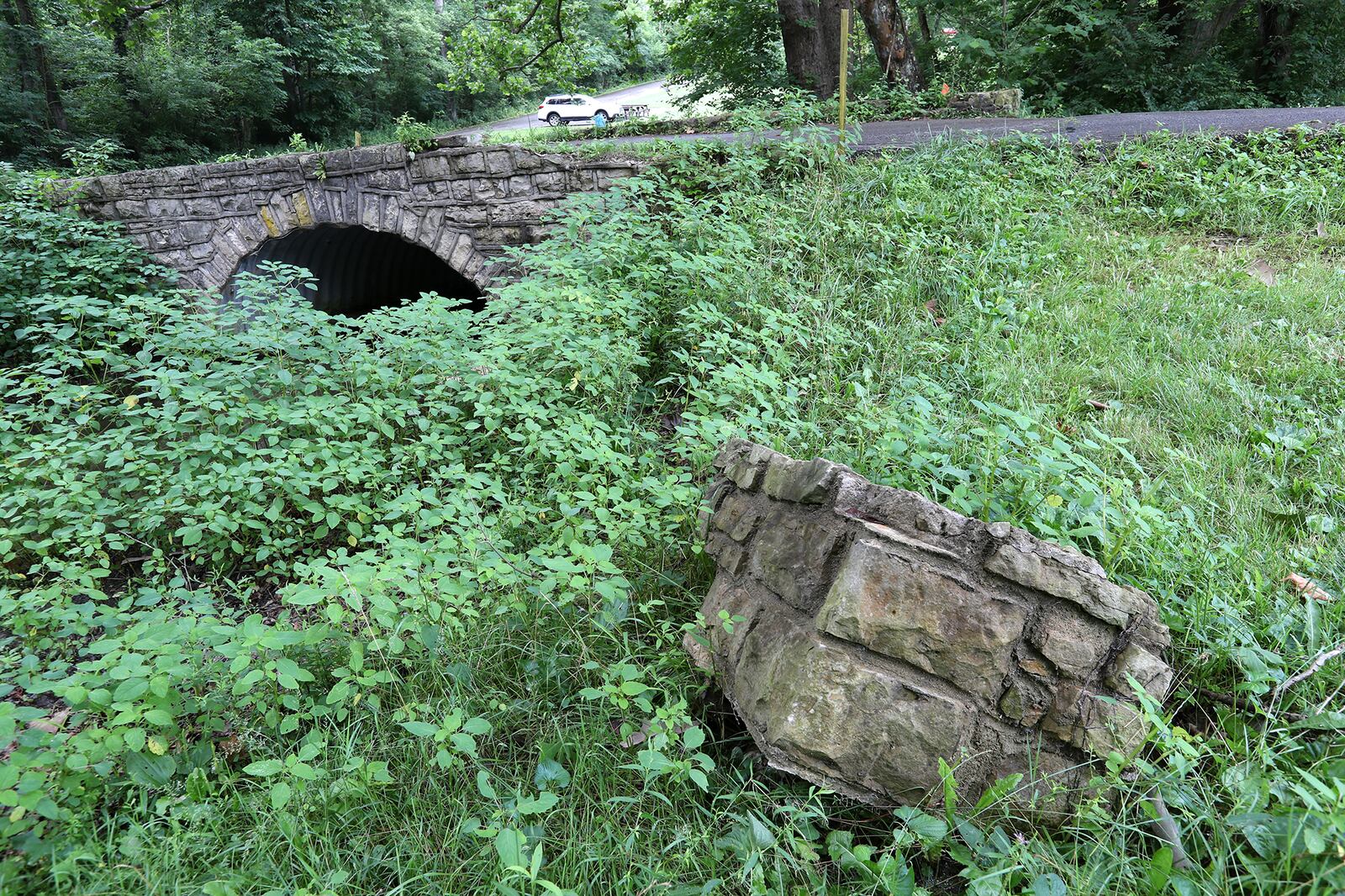 A chunk of the stone face of the old lower bridge in George Rogers Clark Park lies in the grass, broken off from the bridge. The park has asked ODOT to replace the bridge. BILL LACKEY / STAFF 