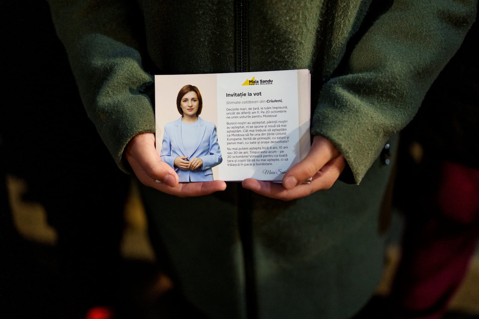 A girl holds a leaflet showing Moldova's President Maia Sandu while listening to her speaking to supporters in Magdacesti, Moldova, Thursday, Oct. 17, 2024, as she seeks a second term in office ahead of a presidential election and a referendum of whether to enshrine in Moldova's Constitution its path to European Union membership taking place on Oct.20. (AP Photo/Vadim Ghirda)