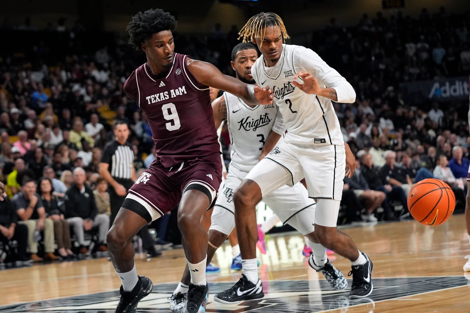 Texas A&M forward Solomon Washington (9) loses control of the ball as he is defended by Central Florida guard Darius Johnson (3) and forward JJ Taylor (2) during the first half of an NCAA college basketball game, Monday, Nov. 4, 2024, in Orlando, Fla. (AP Photo/John Raoux)