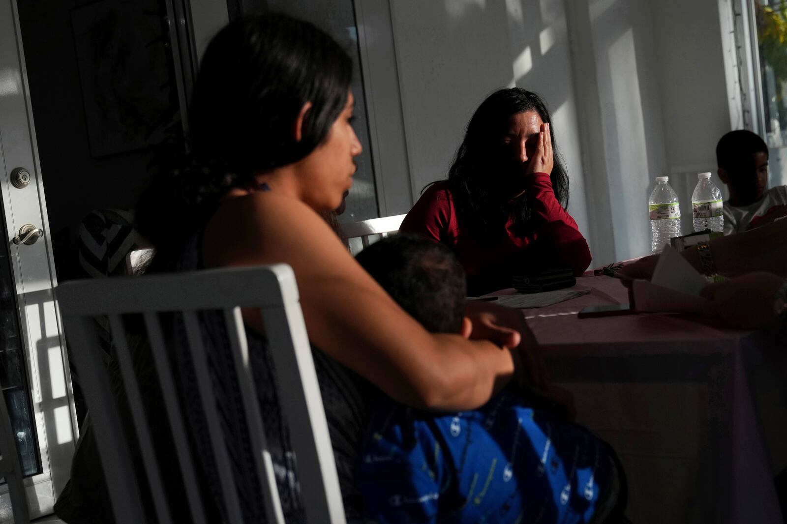 Parents of small children wait to sign documents giving Nora Sandigo legal guardianship of their children if they are detailed or deported, Sunday, Jan. 19, 2025, in Miami. (AP Photo/Marta Lavandier)