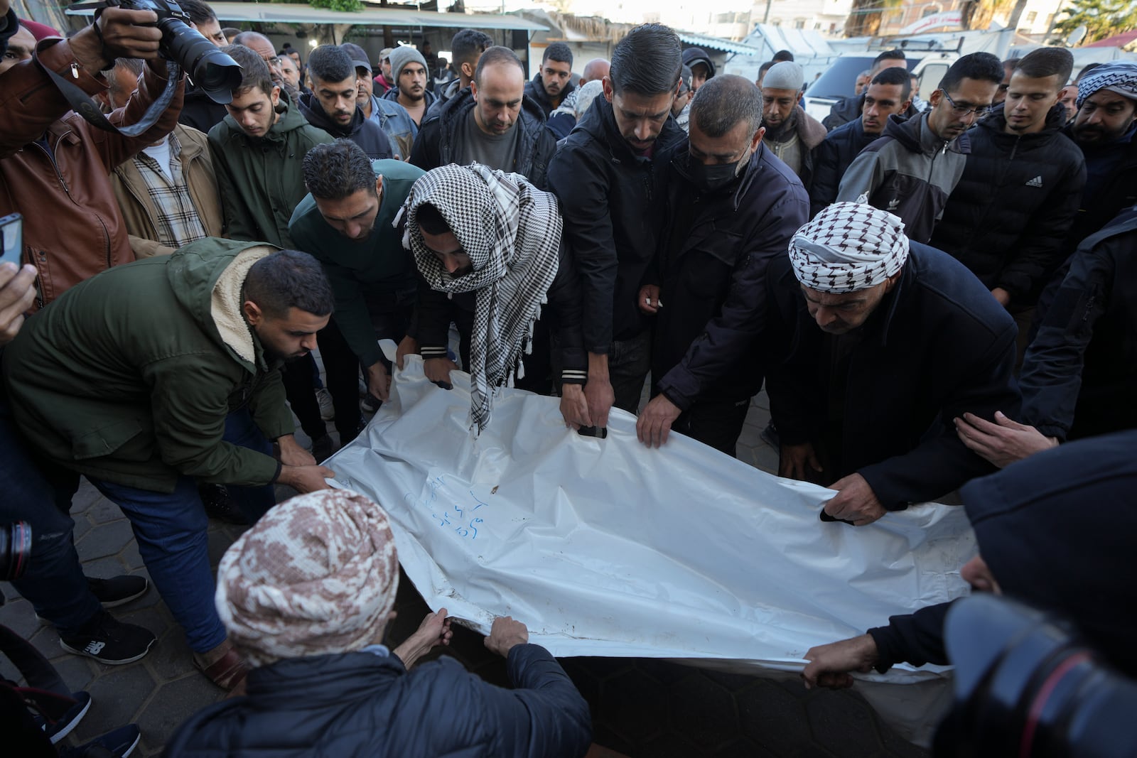 Palestinians carry the body of victim of an overnight Israeli strike, outside a hospital in Deir al-Balah, Gaza Strip, Wednesday, Dec. 4, 2024. (AP Photo/Abdel Kareem Hana)