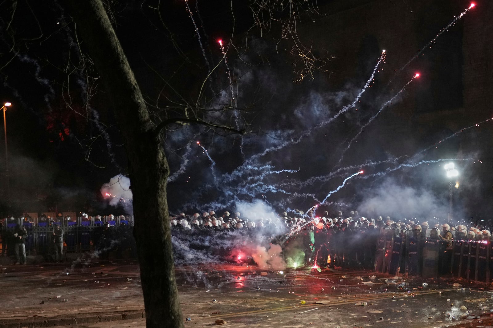 Fireworks thrown by protesters explode over riot police during a protest against the arrest of Istanbul's Mayor Ekrem Imamoglu, in Istanbul, Turkey, Saturday, March 22, 2025. (AP Photo/Francisco Seco)