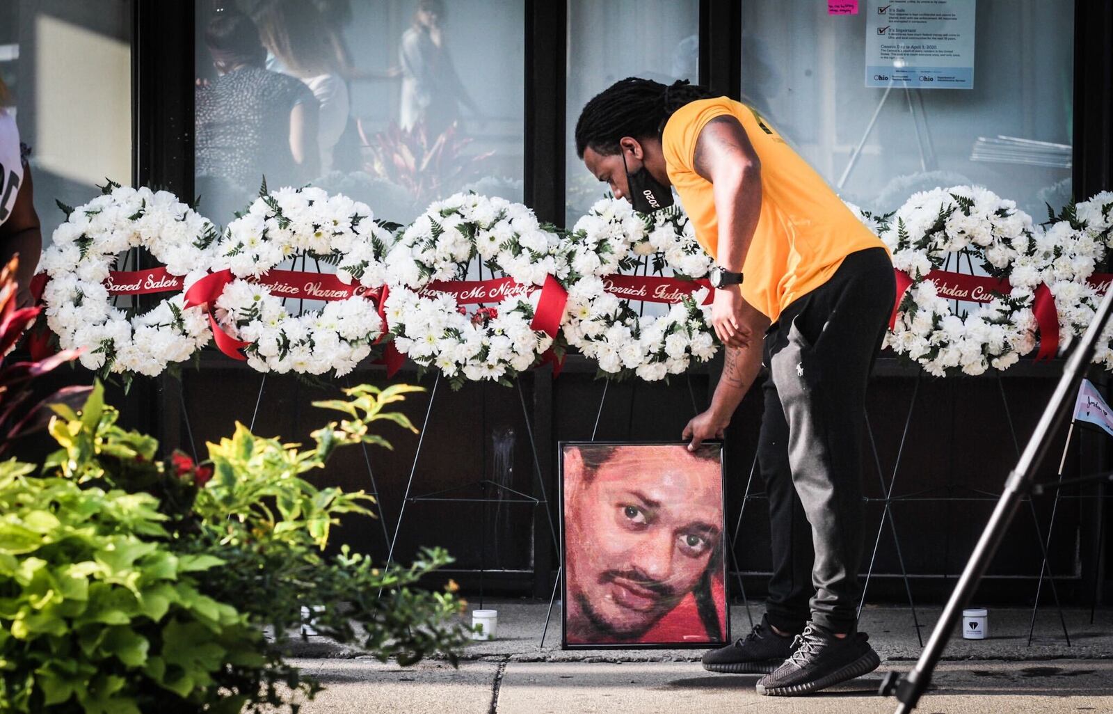 Dion Green places a portrait of his father, Derrick Fudge, on Fifth St. in the Oregon District.