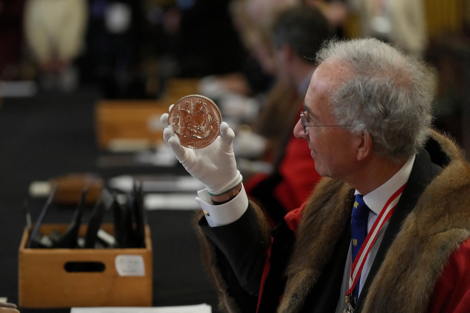 A warden inspects a 500 Pound coin during the "Trial of the Pyx,'' a ceremony that dates to the 12th Century in which coins are weighed in order to make certain they are up to standard, at the Goldsmiths' Hall in London, Tuesday, Feb. 11, 2025.(AP Photo/Frank Augstein)