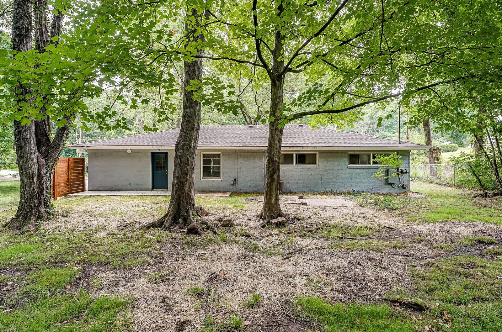 The rear of the home has a concrete patio, wood privacy patio and mature trees.