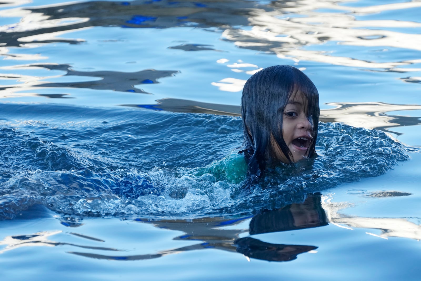 A young girl swims at the dock where fishing boats launch in the village of Siumu, Samoa, on Tuesday, Oct. 22, 2024. (AP Photo/Rick Rycroft)