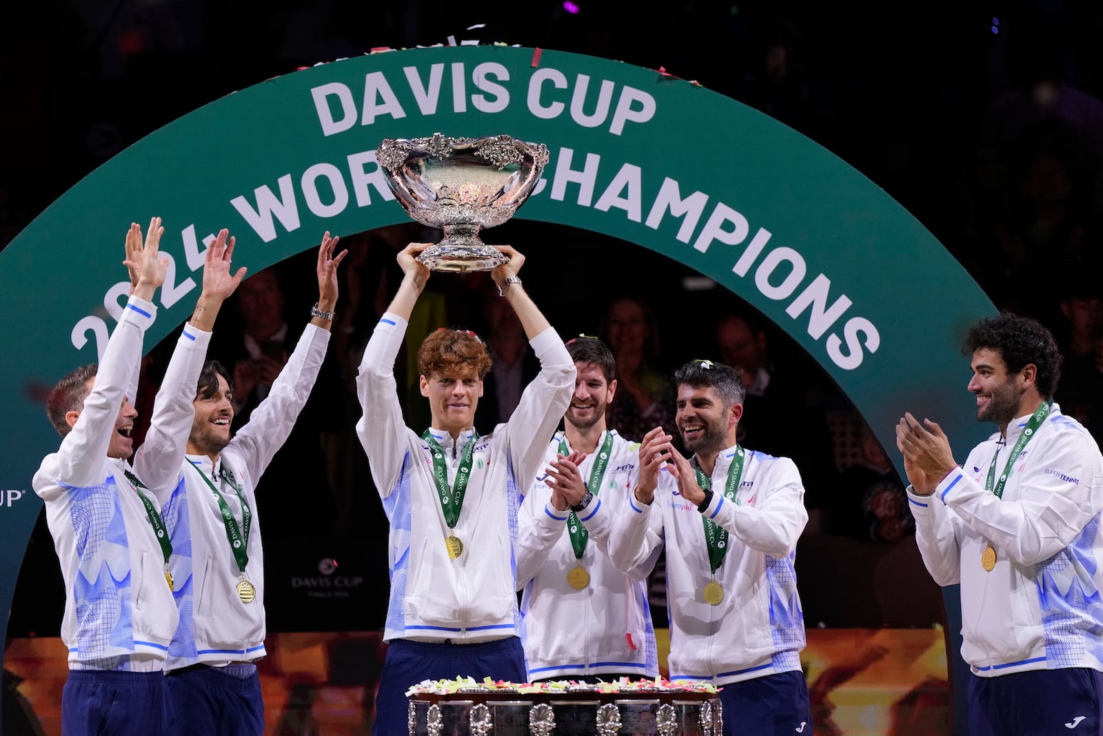 Italy's Jannik Sinner, center, holds the Davis Cup trophy by teammates after the final between Netherlands and Italy at the Martin Carpena Sports Hall in Malaga, southern Spain, as Italy wins its second consecutive Davis Cup title, Sunday, Nov. 24, 2024. (AP Photo/Manu Fernandez)