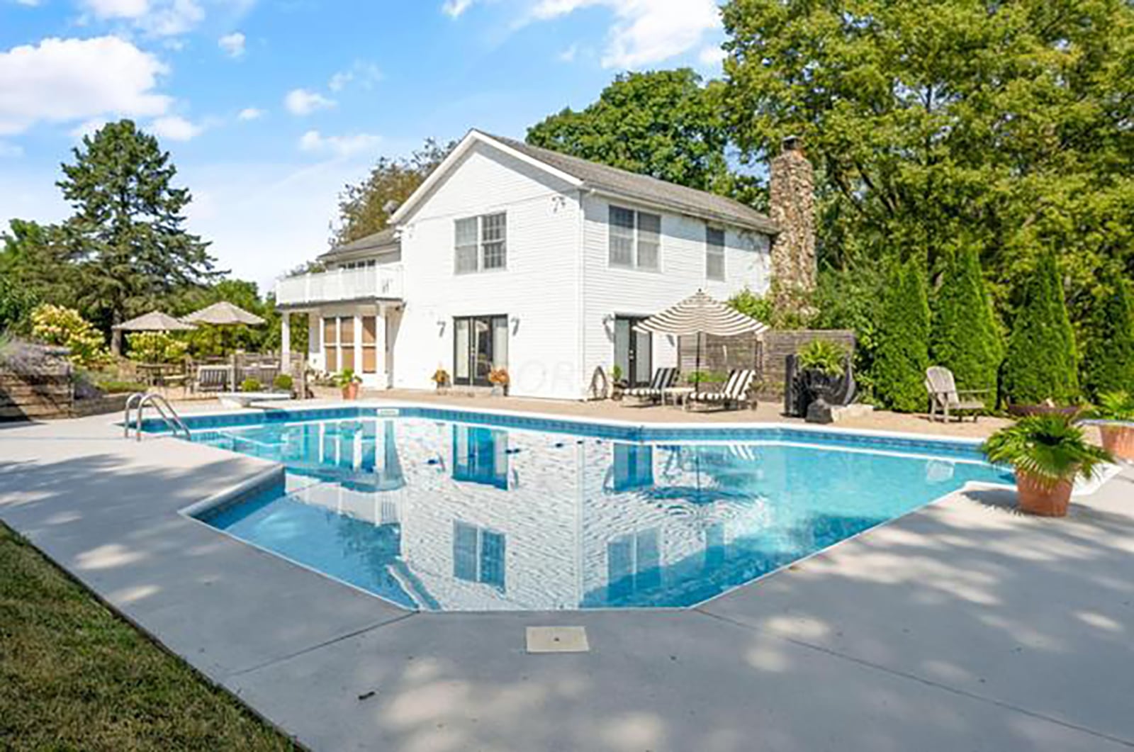 The home has an inground swimming pool surrounded by a concrete patio and pavers