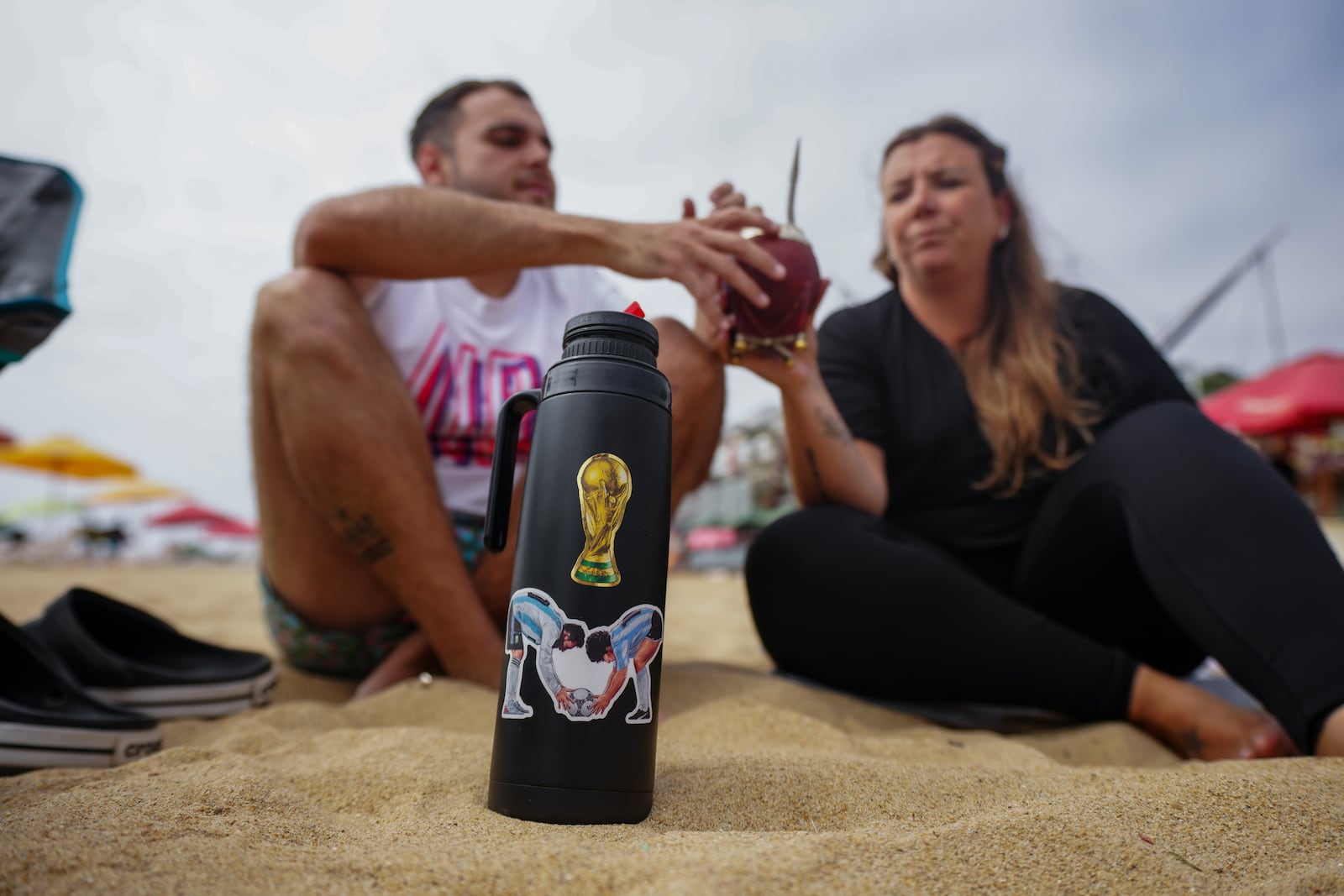 Argentines on vacation share a yerba mate tea while sitting on the sand of Renaca beach in Vina del Mar, Chile, Thursday, Jan. 30, 2025. (AP Photo/Esteban Felix)