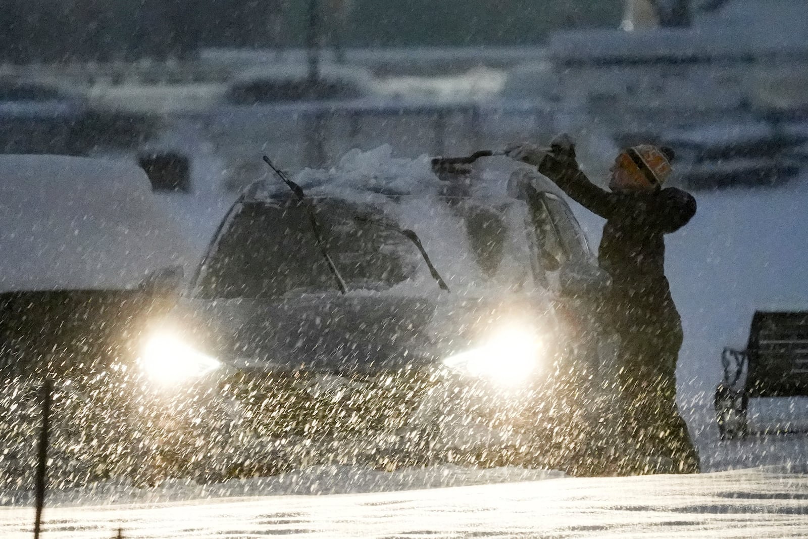 A person clears off a car during a winter snow storm in Washington, Monday, Jan. 6, 2025. (AP Photo/Matt Rourke)