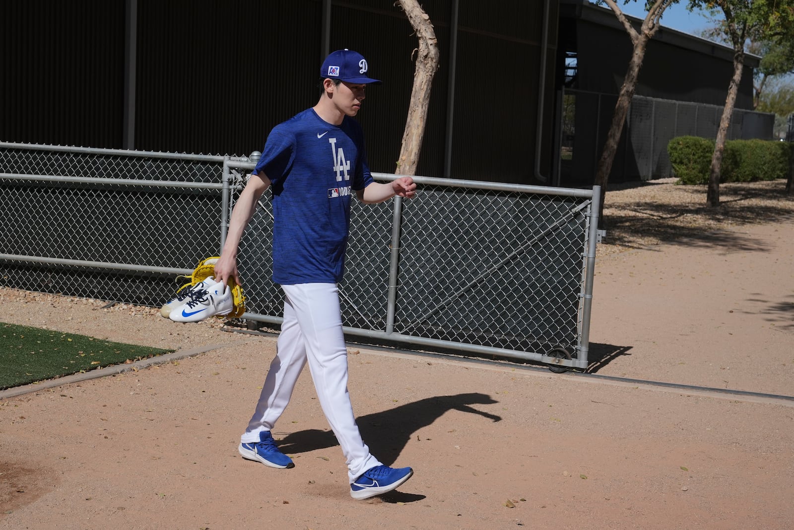 Los Angeles Dodgers pitcher Roki Sasaki, of Japan, walks to a practice field to warm up at the Dodgers baseball spring training facility, Tuesday, Feb. 11, 2025, in Phoenix. (AP Photo/Ross D. Franklin)