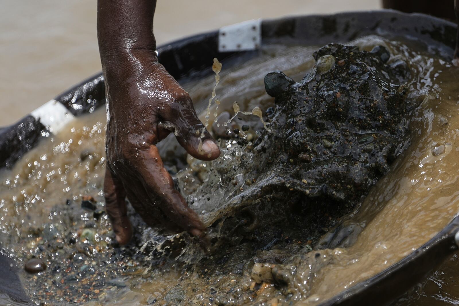 A small-scale miner searches for gold at the Atrato River, in El Arenal, Colombia, Thursday, Sept. 26, 2024. (AP Photo/Ivan Valencia)