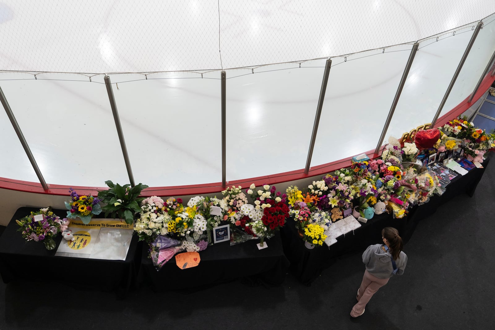 A memorial is seen along the boards at MedStar Capitals Iceplex Sunday, Feb. 2, 2025, in Arlington, Va., for the figure skaters who were among the 67 victims of a mid-air collision between an Army helicopter and an American Airlines flight from Kansas. (AP Photo/Carolyn Kaster)