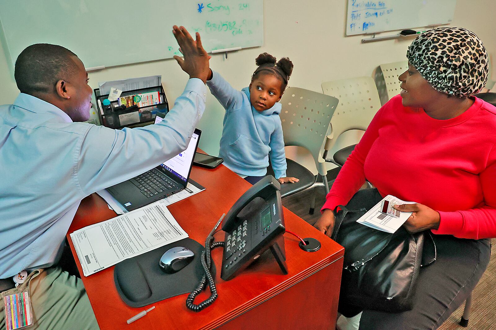 Johnson Salomon, a patient advocate and interpreter at the Rocking Horse Center, gets a high five from Haitian imigrant Snica Leguerre after her mother Lormilia got clarification on some paperwork Wednesday, May 3, 2023 at the Rocking Horse Center. BILL LACKEY/STAFF