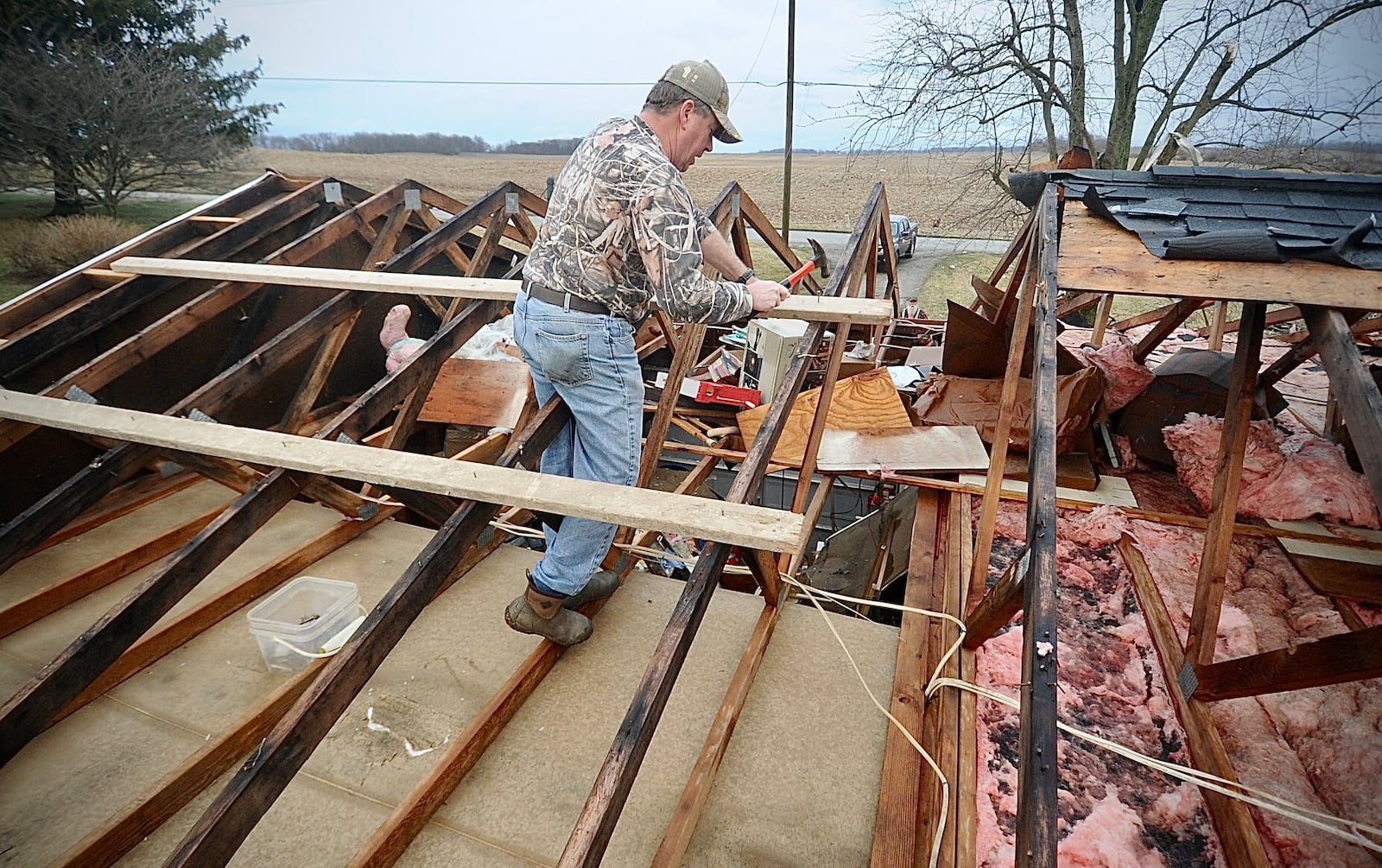 Ted Williams works to put a temporary cover on the roof after a tornado struck his in-laws' home on Newlove Road Wednesday morning, Feb. 28, 2024. William said his in-laws stayed in the middle hallway and both are safe. MARSHALL GORBY/STAFF